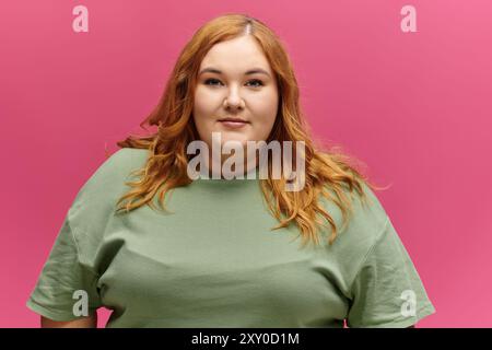 A woman with long red hair smiles confidently while wearing a green shirt. Stock Photo