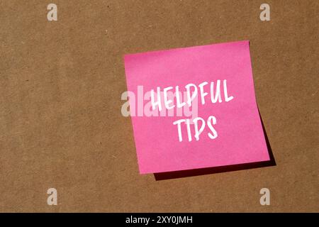 Helpful tips message written on pink paper with cardboard background. Conceptual helpful tips symbol. Copy space. Stock Photo