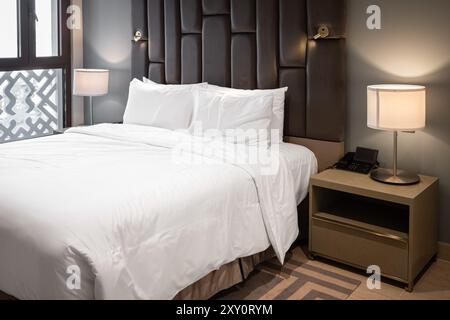 Stylish bedroom with double bed. Modern bedroom interior with a master bed standing with two nightstands lamps. Big comfortable double bed in elegant Stock Photo