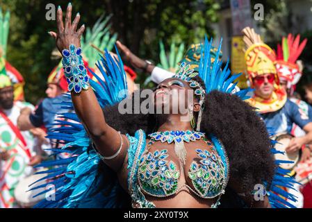 Black female dancer performing at the Notting Hill Carnival Grand Parade 2024. Adult's Day on Bank Holiday Monday. Wearing elaborate feather costume Stock Photo