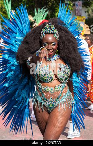 Black female dancer performing at the Notting Hill Carnival Grand Parade 2024. Adult's Day on Bank Holiday Monday. Wearing elaborate feather costume Stock Photo