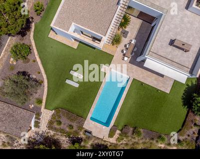 Aerial shot of a contemporary luxury home featuring a large swimming pool, terraces, and landscaped garden Stock Photo