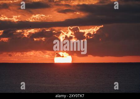 An incredibly vibrant sunset paints the sky over the Atlantic Ocean in shades of orange and red, as seen from the Azores Islands, showcasing the beaut Stock Photo