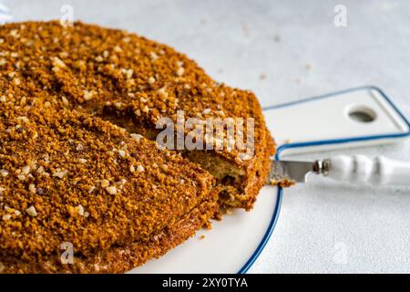 Delicious homemade honey cake, sprinkled with crushed nuts, served on a stylish white plate. Stock Photo