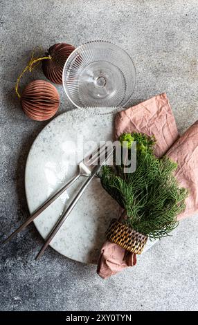 From above view of a stylish Christmas table setting with delicate decorations against a concrete background, adding a minimalistic yet festive touch. Stock Photo
