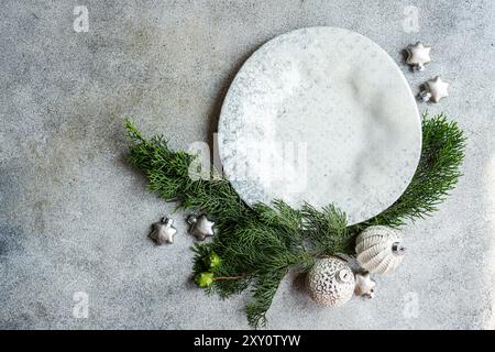 Top view of a festive composition with Christmas decorations, including pine branches and ornaments placed strategically on a textured concrete backgr Stock Photo