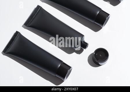 An array of empty black cosmetic tubes neatly positioned against a stark white backdrop, perfect for product mockups and branding presentations. Stock Photo