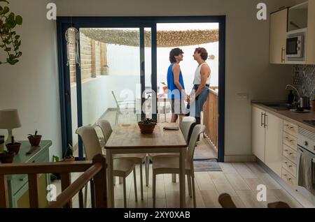 A tender moment between a gay couple on their elegant terrace, where they hold hands and share a connection, showing love and everyday life in a moder Stock Photo