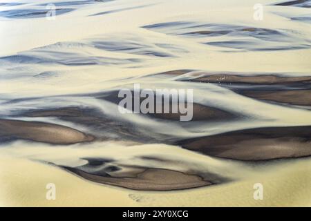Captivating aerial view of a glacial river on the south coast of Iceland, showing striking patterns and contrasts formed by sediment and flowing water Stock Photo