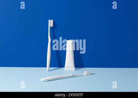 A minimalist display of dental hygiene products, featuring a white toothbrush, a tube of toothpaste, and a dental pick, all against a vibrant blue bac Stock Photo