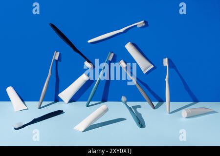 An array of dental care items, including multiple toothbrushes and toothpaste tubes, creatively arranged on a vibrant blue backdrop Stock Photo