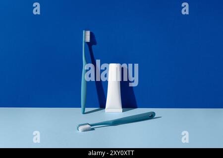 An image showcasing dental hygiene essentials including two toothbrushes and a tube of toothpaste arranged neatly on a bright blue background, emphasi Stock Photo