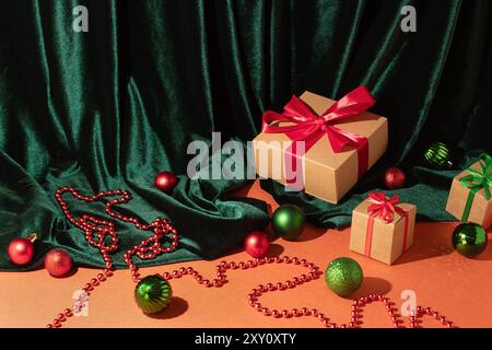 Festive gift boxes with red and green ribbons, surrounded by holiday ornaments and green velvet fabric Stock Photo