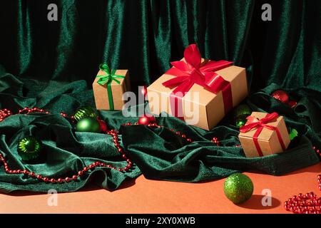 Festive gift boxes with red and green ribbons, surrounded by holiday ornaments and green velvet fabric Stock Photo