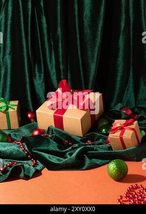 Festive gift boxes with red and green ribbons, surrounded by holiday ornaments and green velvet fabric Stock Photo