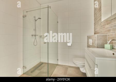 A contemporary bathroom featuring a glass walk-in shower, tiled walls, and a white vanity. Stock Photo