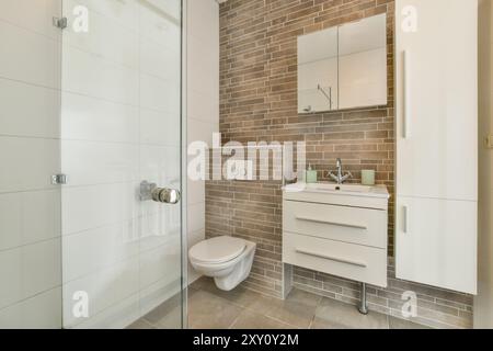 Contemporary bathroom featuring a glass shower enclosure, brown tiled walls, and a white vanity. Stock Photo