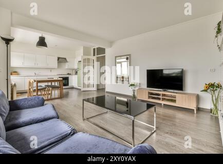 A well-lit modern living room seamlessly transitions into an open kitchen area, featuring contemporary furniture and clean lines. Stock Photo
