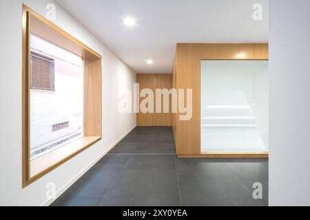 Sleek corridor inside a modern auditorium featuring minimalist interior design with wooden elements, large window, and LED lighting. Stock Photo
