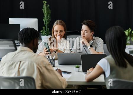 A diverse team of young professionals collaborates on a project, focused on a smartphone. Stock Photo