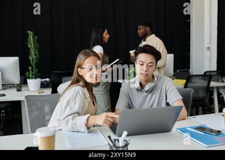 Two young colleagues work together on a laptop, discussing ideas for their new venture. Stock Photo