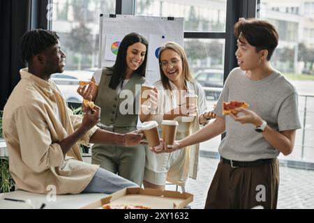 Four colleagues share pizza and coffee during a lunch break in an office setting. Stock Photo