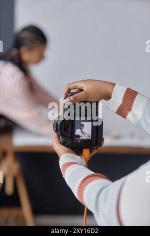 Vertical closeup of female hands holding professional DSLR camera and taking pictures in photo studio copy space Stock Photo