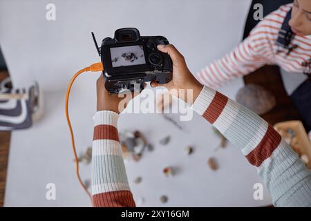 Top view closeup of female hands holding professional camera during product photography photoshoot in studio copy space Stock Photo