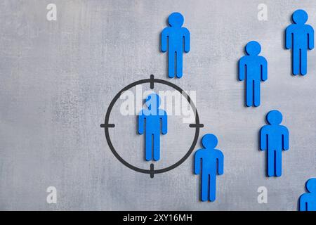 Blue human figures with one in a targeting reticle on grey background. Copy space for text. Recruitment, talent search concept. Stock Photo
