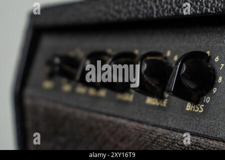 Close-up of black guitar amplifier knobs with numbers on a textured surface. Stock Photo