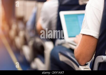 Man typing on a laptop aboard the plane Stock Photo