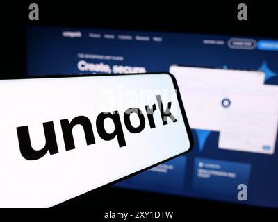 Smartphone with logo of American enterprise application platform company Unqork Inc. in front of website. Focus on center of phone display. Stock Photo
