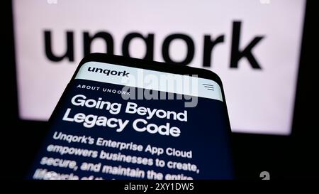 Mobile phone with website of US enterprise application platform company Unqork Inc. in front of business logo. Focus on top-left of phone display. Stock Photo