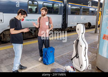 Livorno Italy,Piazza Dante,Livorno Centrale central train railway station,platform passengers waiting,men friends musicians,musical instrument case,It Stock Photo