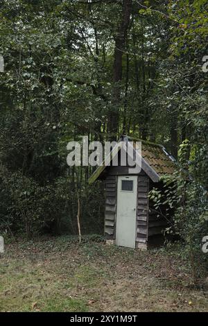 Ranst, Belgium - October 11 2023: A small, rustic hut nestled in a dense forest. Surrounded by tall trees and lush greenery, the hut blends with its n Stock Photo