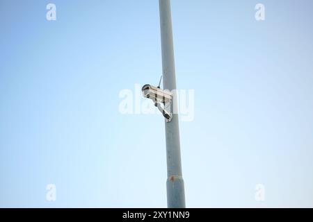 security camera hanging on power pole isolated on blue background Stock Photo