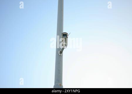 security camera hanging on power pole isolated on blue background Stock Photo