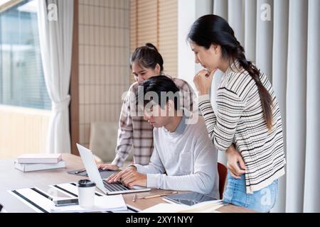 Focused Group of Students Collaborating on Laptop in Classroom Stock Photo