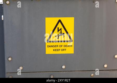 A yellow and black danger of death warning sign on an electric transformer Stock Photo