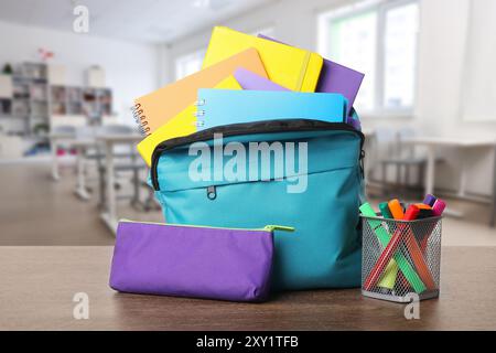 Light blue backpack with stationery on school desk in classroom Stock Photo