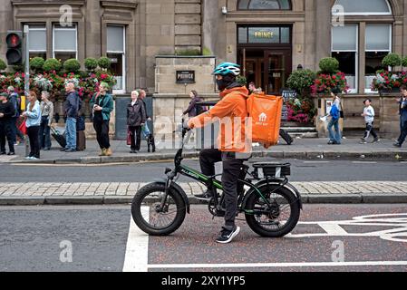 Just Eat food delivery cyclist wait at traffic lights on Prince Street, Edinburgh, Scotland, UK. Stock Photo