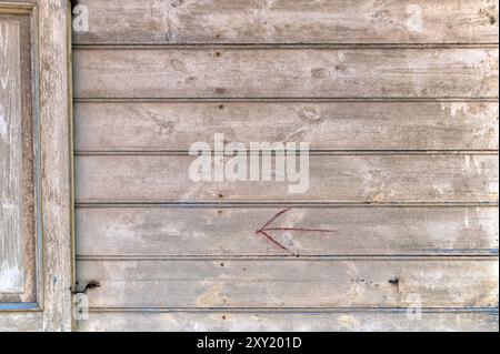 A weathered wooden wall with a faint red arrow indicating direction, showing age and history. Stock Photo