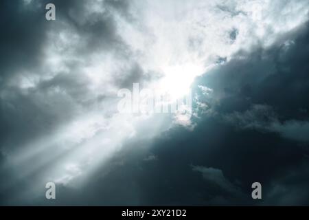 Sunbeam shining through dark storm cloudy sky Stock Photo