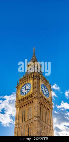 Low angle view of two sides of the Big Ben Clock Tower seen in great detail of its golden ornamentation and cross on the capital on a bright day with Stock Photo