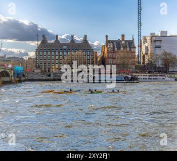 Friends and family doing water sports leisure activity in kayaks and canoes on the River Thames passing by and ferries and tourist recreational boats Stock Photo