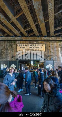 Entrance under the railway bridge to the modern Borough Market, with the old Lee Brothers Potato Merchants sign above the entrance to the market estab Stock Photo
