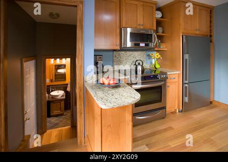 Half of kitchen showing stove, refrigerator and small bathroom down stairs Stock Photo