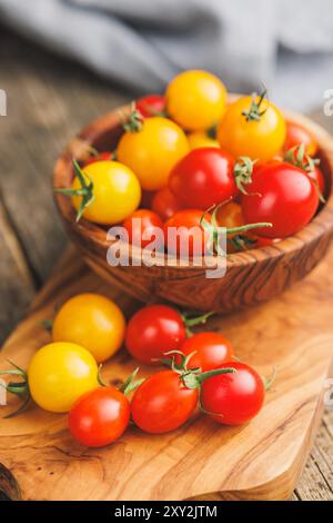 Different colorful cherry tomatoes on a wooden cutting board. Stock Photo