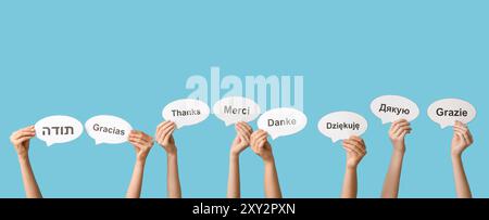 Hands holding speech bubbles with text THANK YOU in different languages on blue background Stock Photo