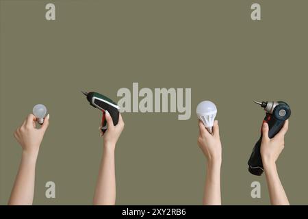 Electrician hands with light bulbs and tools on green background Stock Photo